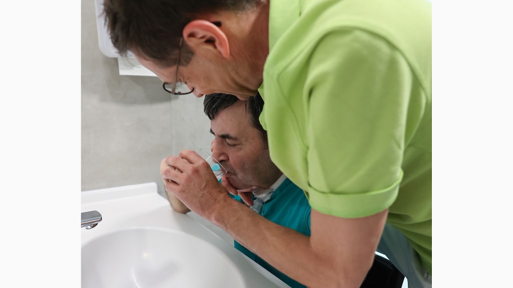 Therapeut unterstützt einen Patienten bei der Mundhygiene